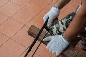 un hombre está cortando madera con una sierra de mano foto