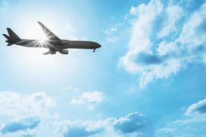 Silhouette airplane in the blue color tone sky with sun light from behind photo