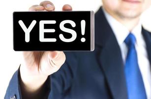 Word on mobile phone screen in blurred young businessman hand over white background, business concept photo