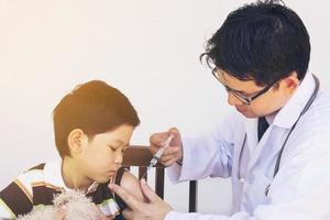 niño asiático enfermo siendo tratado por un médico varón foto