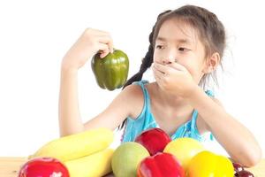 Asian girl is showing dislike vegetable expression over white background photo