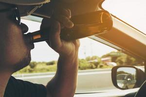 Man drinking beer while driving a car photo