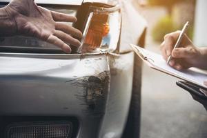 agente de seguros que trabaja durante el proceso de reclamación de accidentes de coche en el lugar - concepto de reclamación de seguros de personas y coches foto