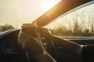 Lady driving car while holding a cup of coffee photo