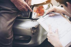 Insurance agent working during on site car accident claim process - people and car insurance claim concept photo