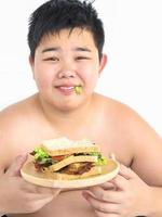 A boy is happily eat at sandwich. Photo is focused at sandwich.