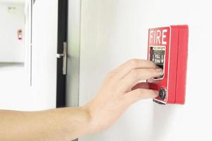 Man is reaching his hand to push fire alarm hand station photo