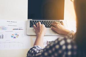 Business woman is working with laptop computer and chart or graph on a table photo