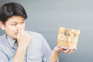 Man showing bad smell expression with old fungi decay bread