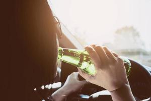 Woman drinking beer while driving a car photo