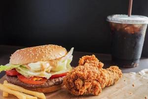 hamburguesa frita con pollo frito y refresco sobre fondo de espacio de copia negra foto