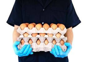 un hombre lleva una bandeja de huevos de 3 capas para mantenerse seguro en casa poniendo guantes sanitarios durante la propagación del virus corona covid-19 - personas que mantienen alimentos en el concepto de período de propagación viral covid-19. foto
