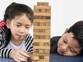 Children is playing a wood blocks tower game for practicing their physical and mental skill photo