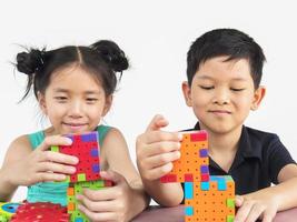 los niños asiáticos están jugando un juego creativo de bloques de plástico para practicar sus habilidades físicas y mentales foto