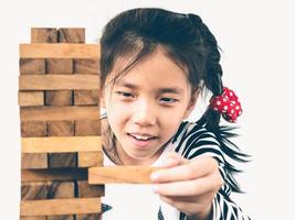 un niño asiático está jugando a la torre de bloques de madera para practicar habilidades físicas y mentales foto