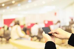 A man is using telephone over colorful blurred bokeh light in office and people background photo