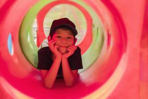 Niño de 7 años en un patio de juegos de tubo rojo foto