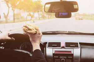 hombre manejando auto mientras come hamburguesa foto