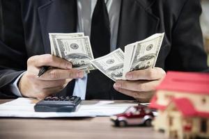 hombre de negocios contando dinero billete de dólar calculando préstamos para el hogar y el automóvil - concepto de bienes raíces de estilo de vida de seguro financiero personal foto
