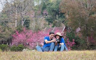 Asian couple happy taking photo in beauliful nature sakura flower garden in Doi Ang Khang, Chiangmai Thailand