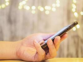 Man hand using -looking mobile phone with light bokeh background photo