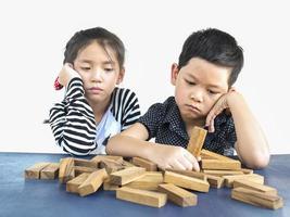 los niños están jugando jenga, un juego de torre de bloques de madera para practicar los niños están jugando jenga, un juego de torre de bloques de madera para practicar su habilidad física y mentalsu habilidad física y mental foto