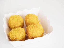 Bolas de queso en un recipiente de papel sobre fondo blanco. foto