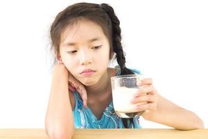 Asian girl is showing dislike drinking milk expression over white background photo