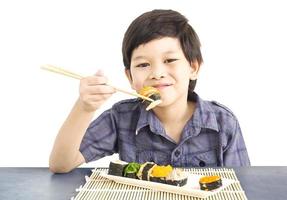 Chico encantador asiático está comiendo sushi aislado sobre fondo blanco. foto