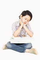 Un niño asiático de 7 años se siente aburrido con un montón de libros sobre fondo blanco. foto