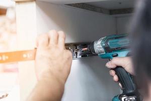 Carpenter is working with furniture assembly using electric screwdriver - technician onsite work using hand tools concept photo