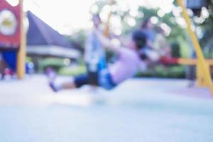 Blurred photo of child is playing swing in a park