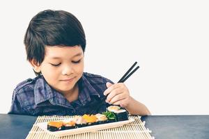 foto de estilo vintage de un niño encantador asiático está comiendo sushi