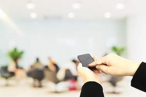 A man is using telephone over blurred bokeh light in office and people background photo