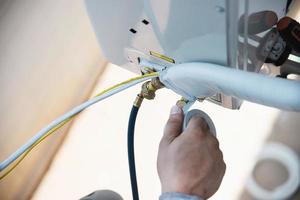 Man is installing wall compressor of air conditioner during hot season photo