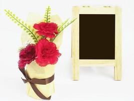 Small blackboard with red artificial flower over white background photo