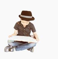 Vintage photo of 7 years old Asian traveler boy is happily sitting and looking at a map while pointing up his index finger isolated over white