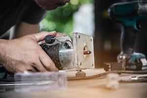 hombre que prepara la máquina herramienta cortadora de laminado del enrutador eléctrico - concepto de taller de carpintería foto