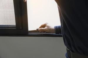 Man doing aluminum frame with wire screen door and window installation work in construction site photo