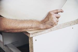 Carpenter making wooden built-in furniture attaching laminate surface photo