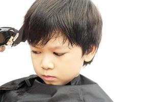 un niño se corta el pelo con un peluquero aislado sobre fondo blanco foto