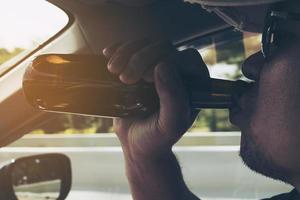 Man drinking beer while driving a car photo