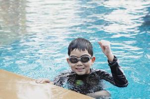 niño feliz asiático jugando en la piscina foto