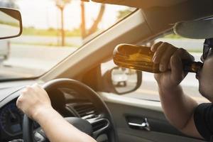 Man drinking beer while driving a car photo