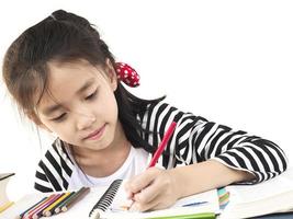 una chica encantadora está haciendo la tarea, coloreando o dibujando un libro foto