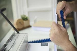 Man making report using comb binding machine - people working with stationary tools concept photo