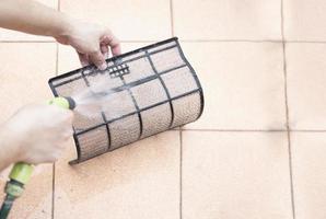 Air conditioner maintenance man cleaning  cover during hot season in Thailand photo