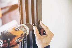 Man doing aluminum frame with glasses and wire screen door and window installation work in construction site photo