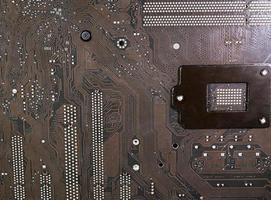 The surface of the motherboard, dark brown, has a pattern of data paths, and the current has a point caused by lead solder. It's the circuit board under the CPU. photo