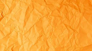 The orange paper background is wrinkled, creating a rough texture with light and shadow. photo
